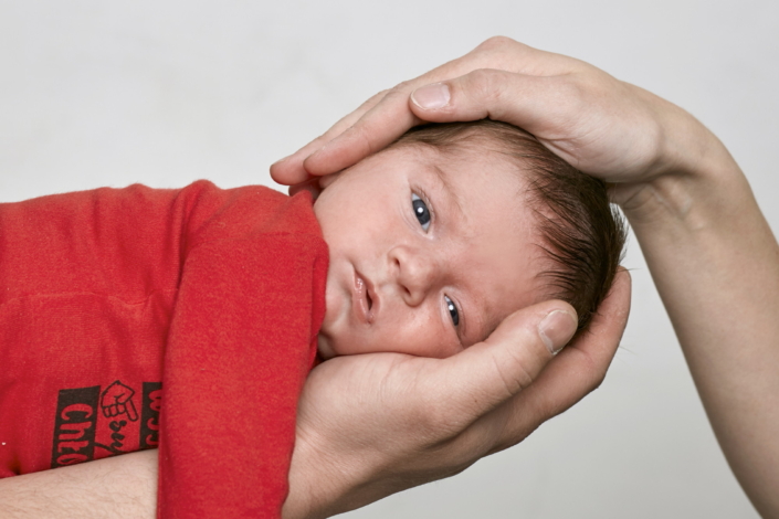 Babys Kopf gehalten von den Händen der Eltern