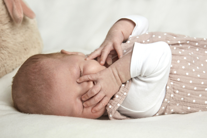 Baby hält Hand vors Gesicht